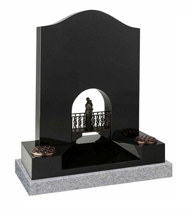 Black granite headstone with embraced couple standing on decorative bridge within arched opening